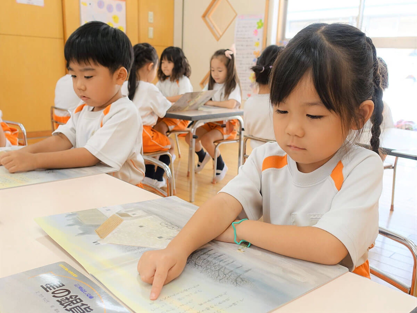 漢字かな交じり絵本を指差しながら音読する様子